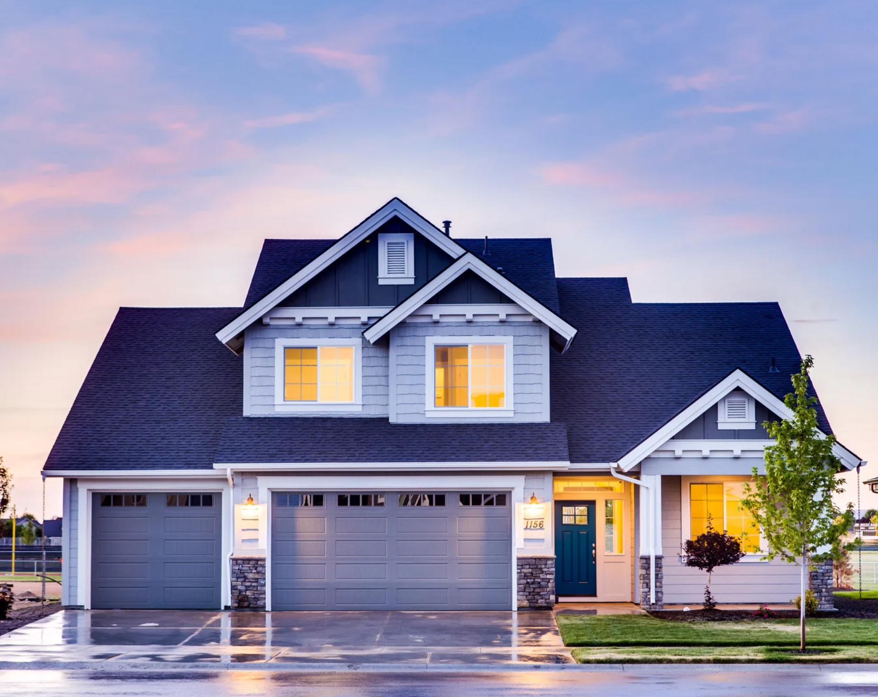 Image of a house with lights on and sunset in background